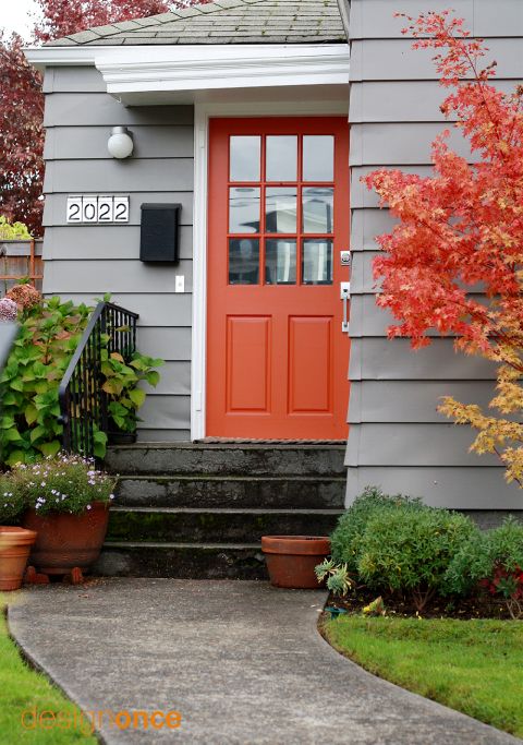 bold orange front door and a tree with orange leaves