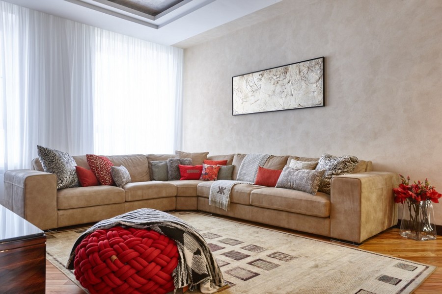 1-4-contemporary-style-interior-design-living-room-light-beige-walls-floor-huge-big-corner-sofa-couch-pillows-rug-red-accents-ottoman-floor-vases-artwork-curtains-stretch-ceiling