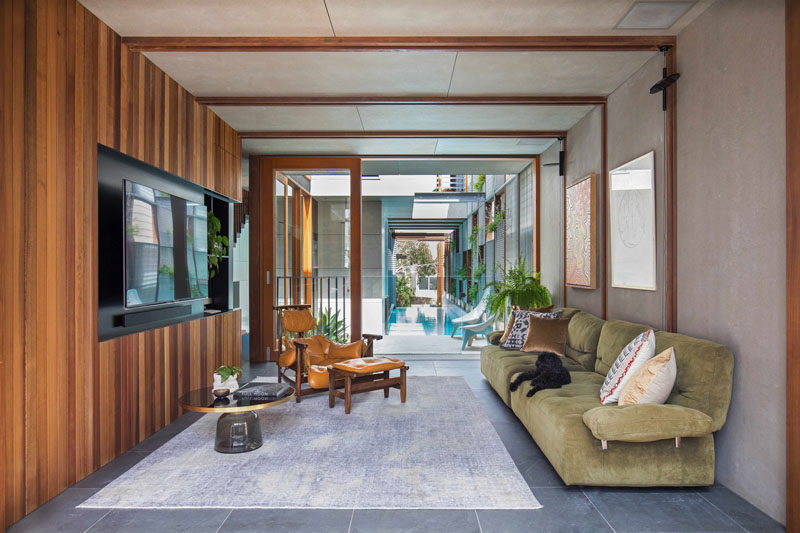 This contemporary media room has a wood accent wall and sliding glass doors that open up to the pool deck and the above ground swimming pool.