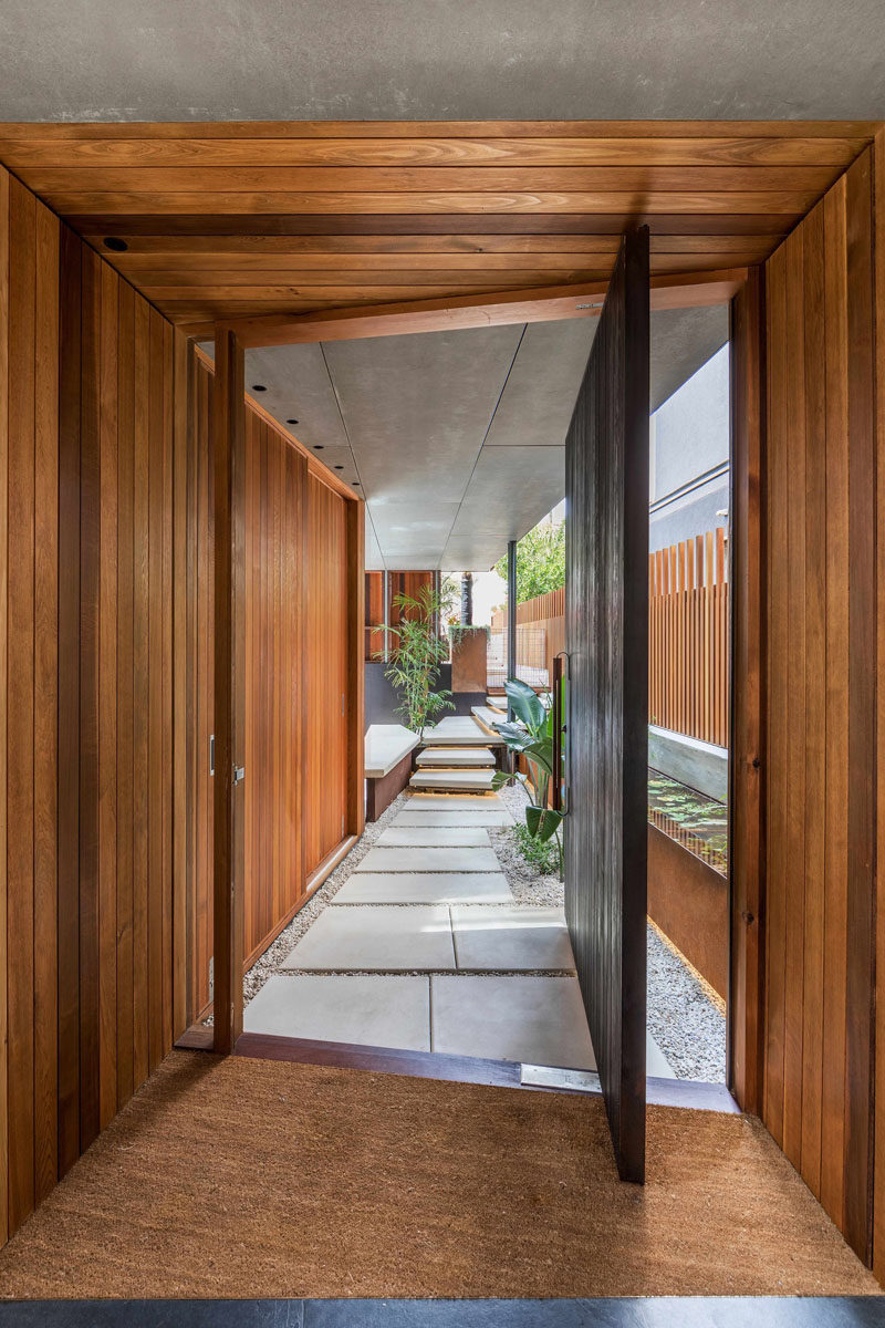A small path leads from the front of the house to the large pivoting wood front door that sits on an angle.