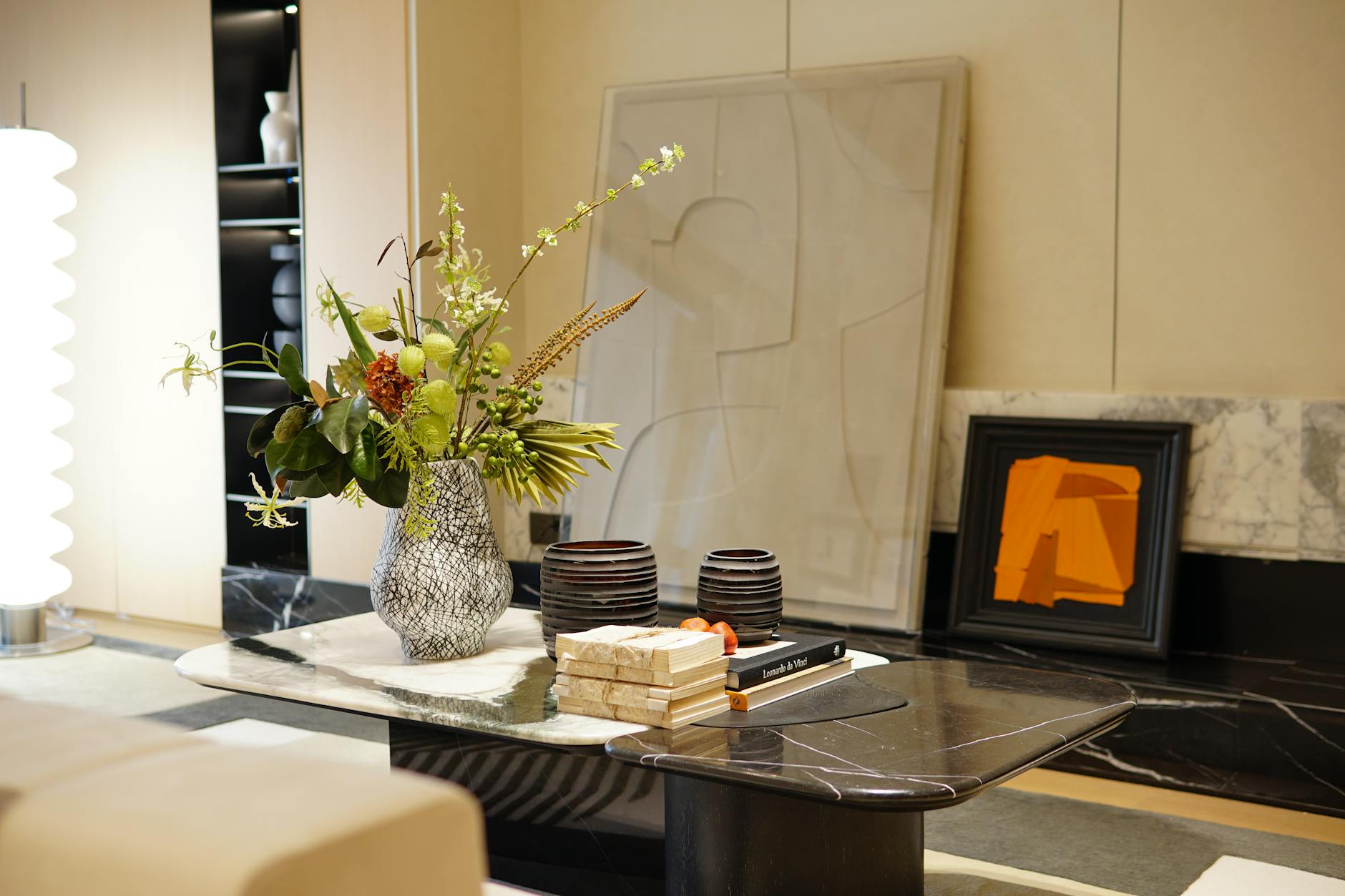 A stylish modern interior with a marble table featuring a decorative flower vase and artwork.