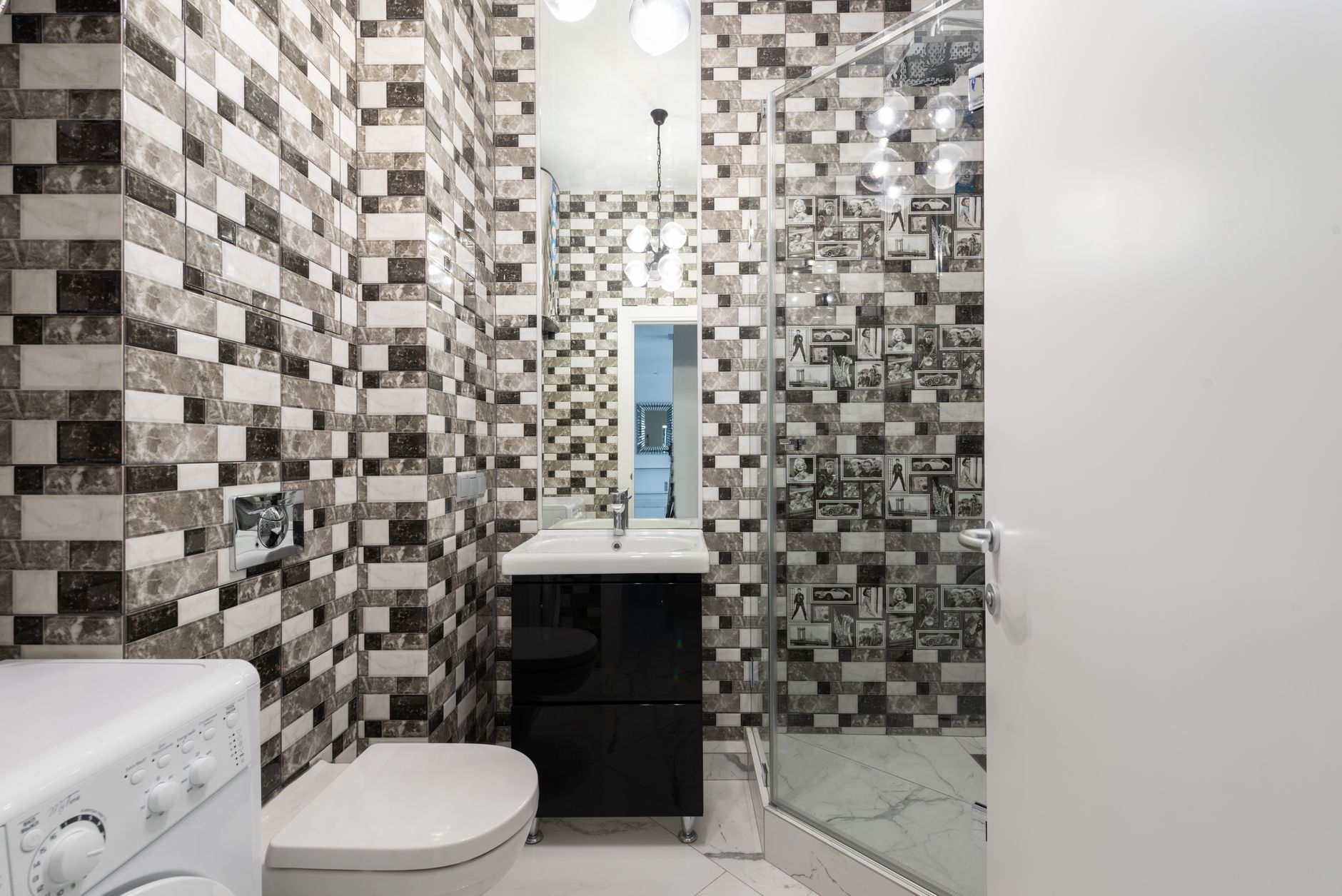 Interior of bright washroom with washing machine near toilet next to shower and sink
