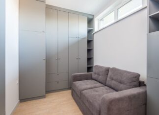 9 Lighting Tricks That Make Small Spaces Feel Bigger and Brighter Sleek and modern apartment interior featuring grey wardrobe and sofa, ideal for space-saving living.