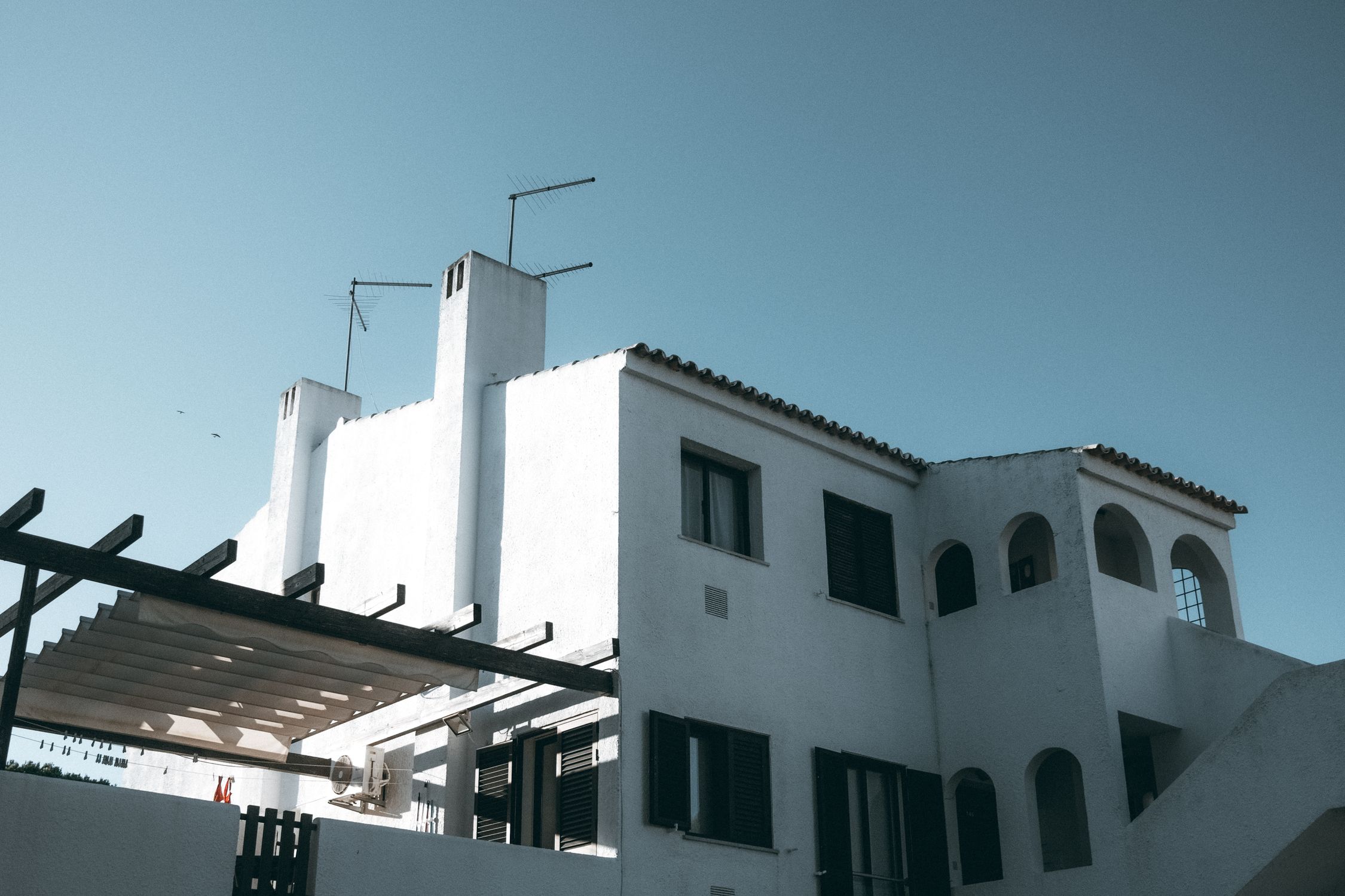 White modern residence with arched windows under a clear sky