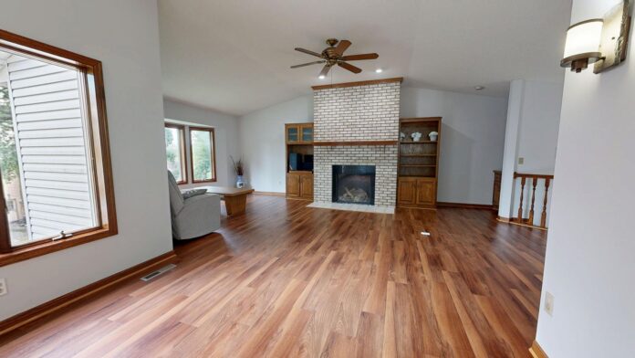 Modern living room with wooden floors and brick fireplace.