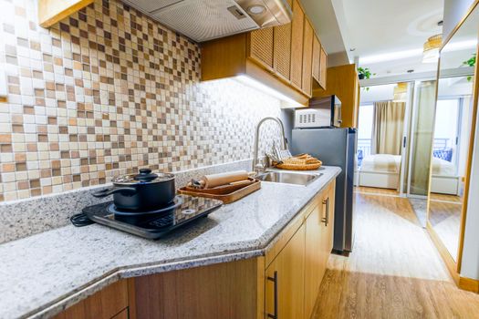 Spacious modern kitchen with induction cooktop, granite countertops, and wooden cabinets in a bright apartment.