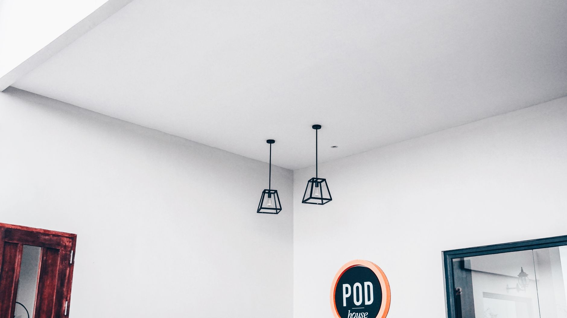Modern minimalist interior featuring geometric pendant lights and a POD sign.