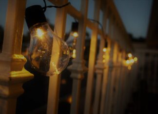 8 Outdoor Lighting Ideas That Make Backyard Evenings Magical Warm glow from string lights hanging on a railing during evening twilight.