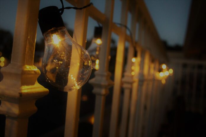 pexels-1025410 Warm glow from string lights hanging on a railing during evening twilight.