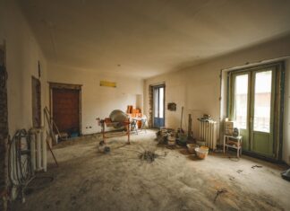 8 Home Renovation Mistakes That Cost You Time and Money Wide view of a sunny room under renovation with construction materials and tools present, ideal for home improvement concepts.