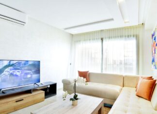 9 Small Apartment Storage Hacks That Actually Create Extra Space Bright living room featuring modern decor with sofa, TV, and abstract art.