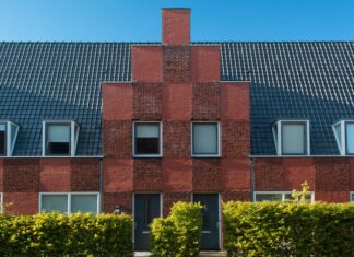 8 Architectural Details That Give Any Home Timeless Curb Appeal Contemporary brick townhouse facade with neat hedge under clear blue sky.