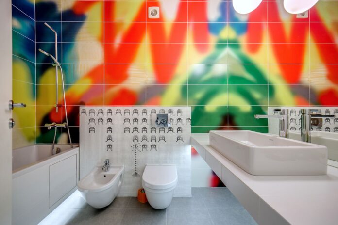A vibrantly designed bathroom featuring colorful tiles, a bathtub, sink, and toilet.