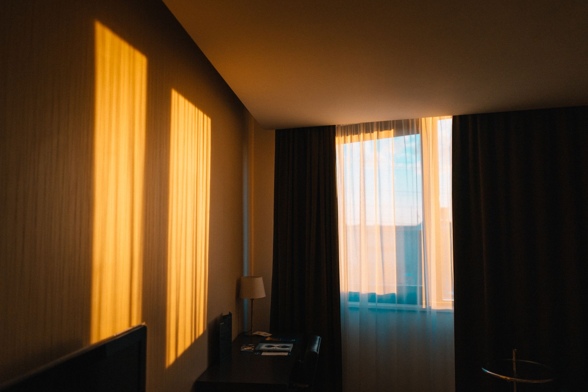 A contemporary bedroom draped in warm morning light filtering through the window.