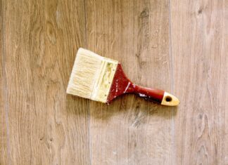 8 DIY Furniture Upcycling Projects That Give Old Pieces New Life A used paintbrush lying on a wooden floor, ideal for renovation and DIY themes.