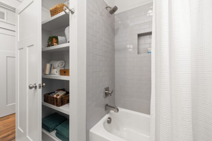 pexels-36777570-2 Bright and clean modern bathroom with grey tiles, shower, and organized shelving.