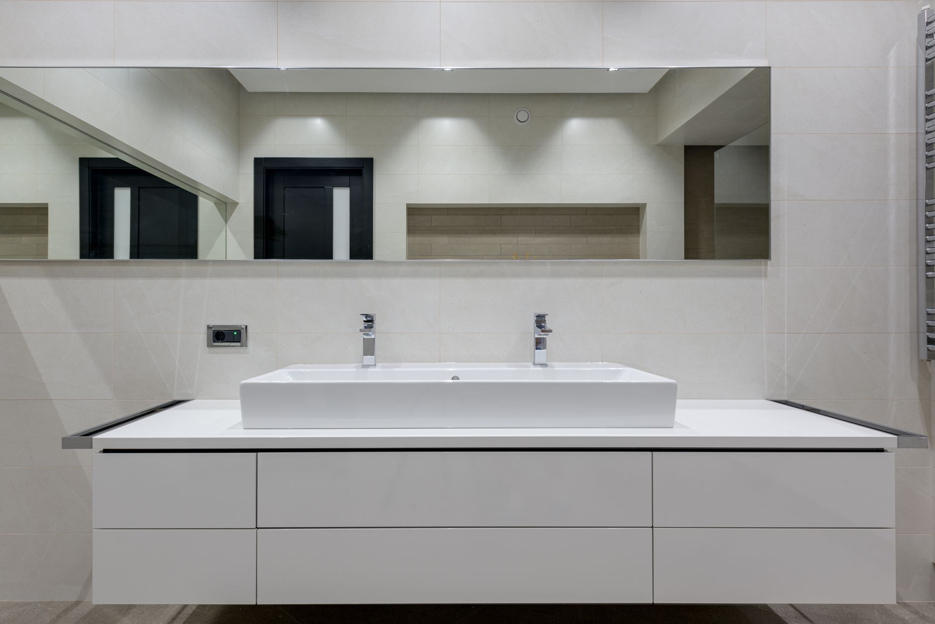 Stylish bathroom with mirror over white table with double vessel sink and towel warmer