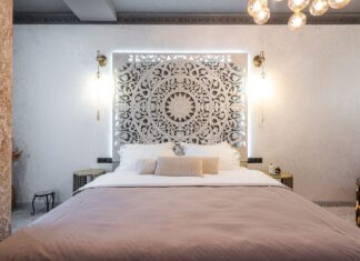 9 Statement Headboard Ideas That Transform Any Bedroom Soft bed with cushions and pillows against wall with symmetrical ornament between luminous lights