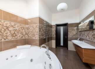 9 Bathroom Flooring Ideas That Balance Style and Durability Interior of contemporary bathroom with round ceramic bathtub and sink and wooden cabinet in daytime
