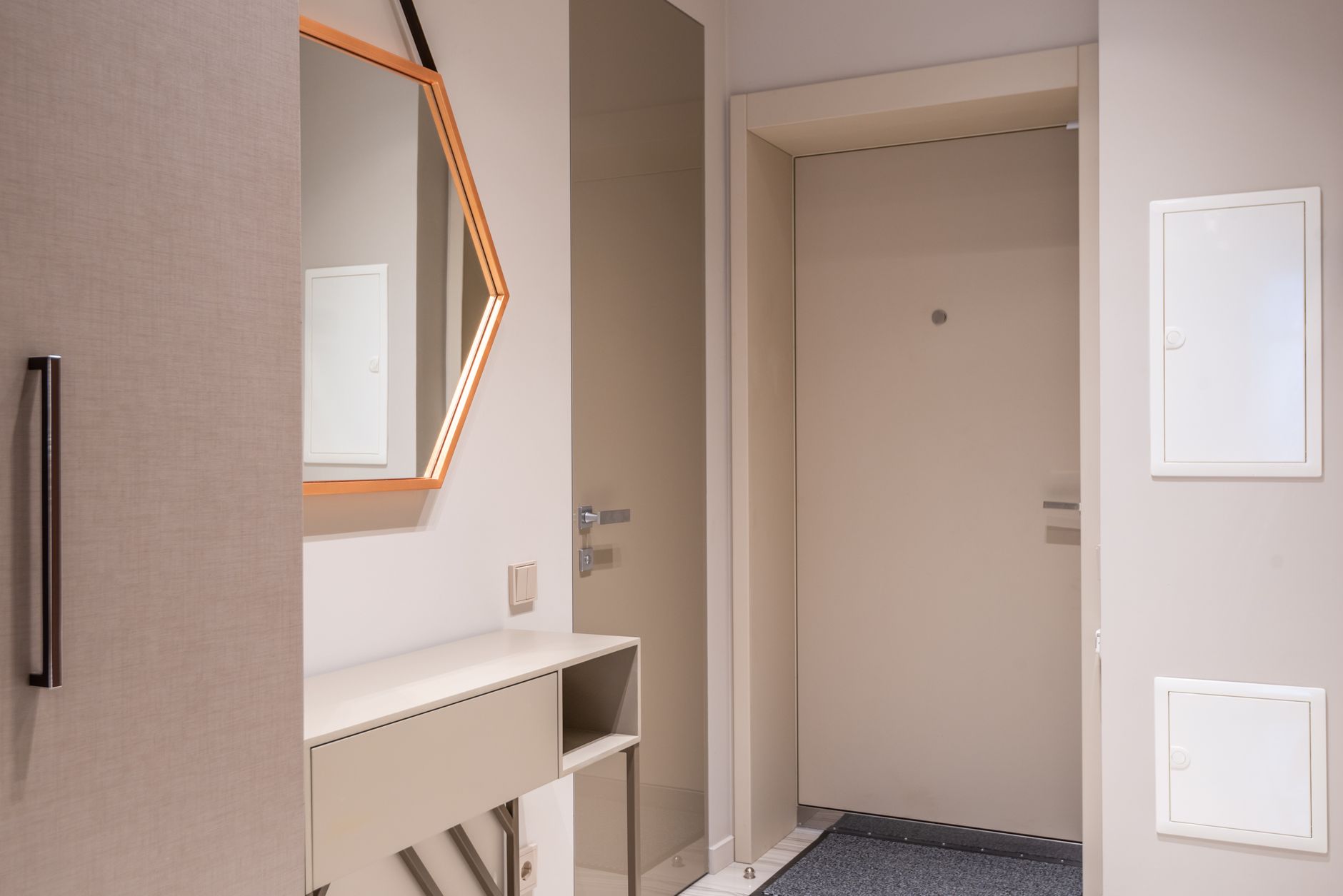 Contemporary corridor interior with beige doors and cabinet under hexagonal shaped mirror at home