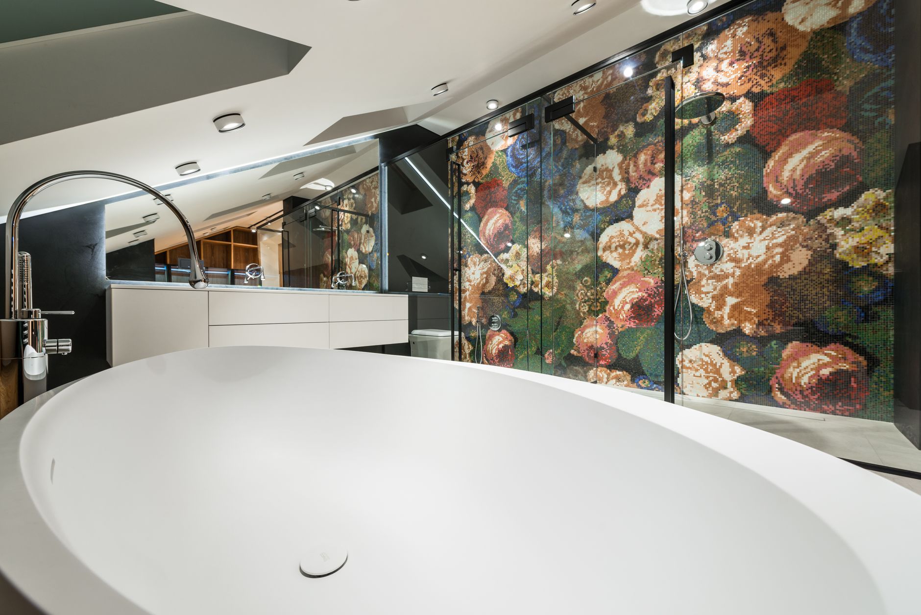 Oval shaped bathtub against shower room with floral ornament on wall in contemporary bathroom with lamps in house