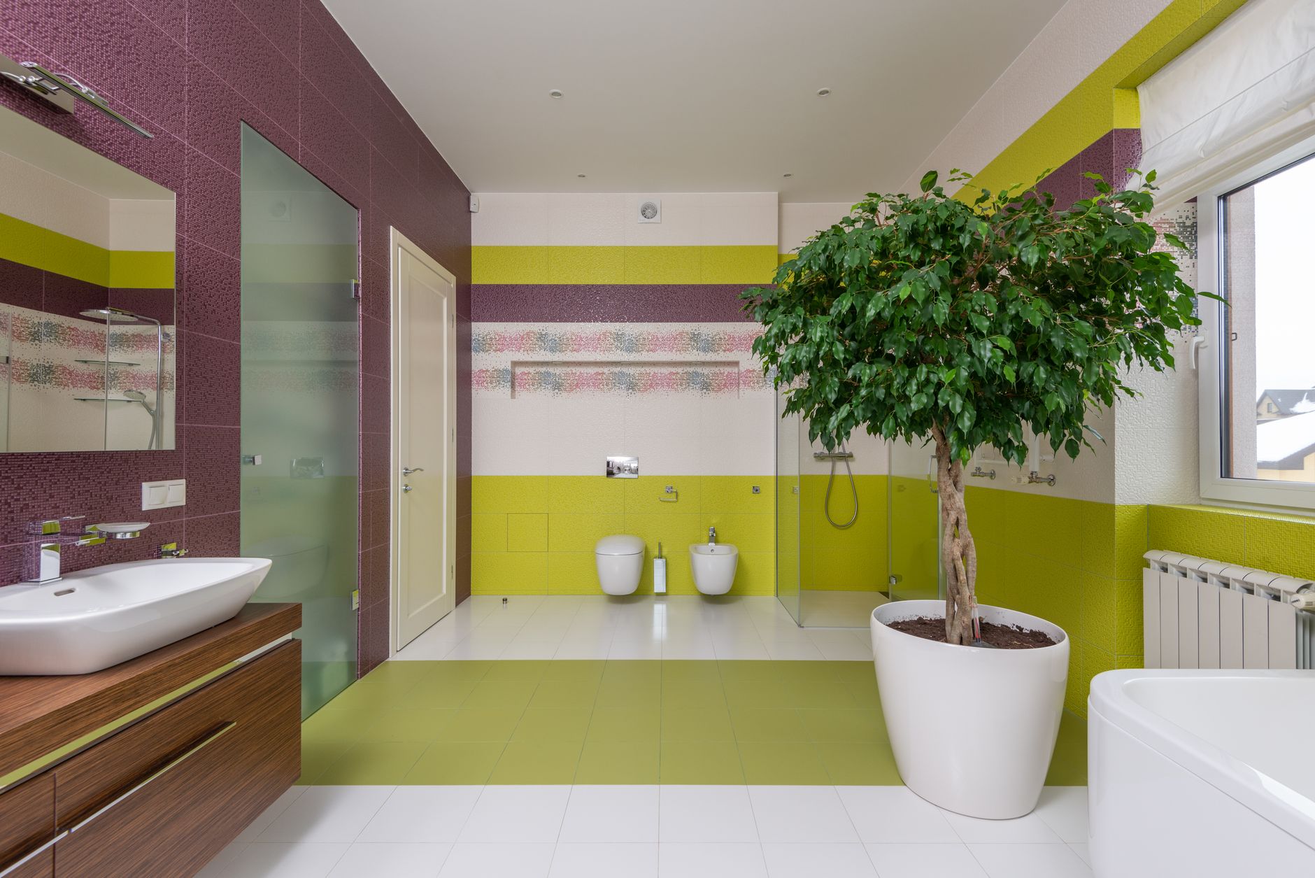 Interior of modern master bathroom with colourful walls and ceramic sink with mirror and potted plant near window
