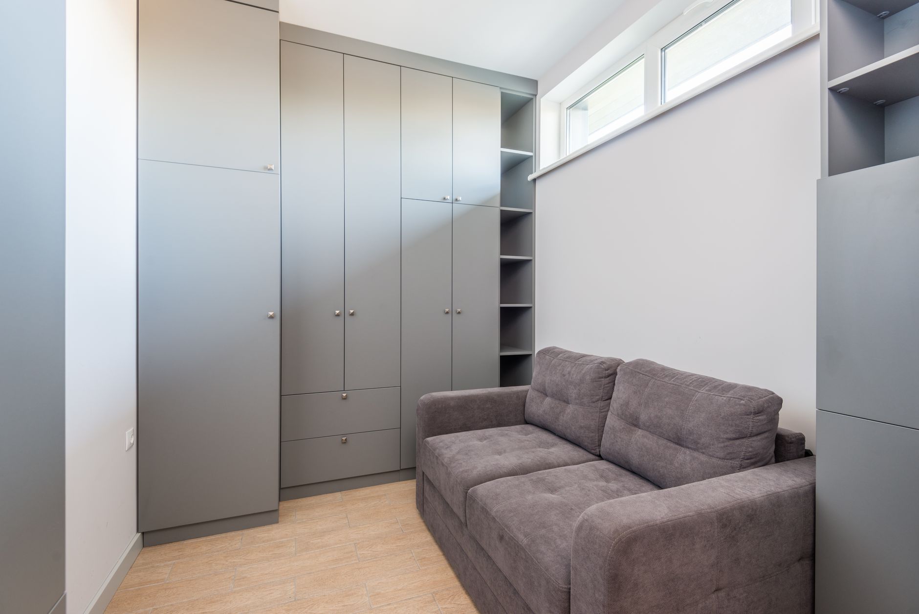 Sleek and modern apartment interior featuring grey wardrobe and sofa, ideal for space-saving living