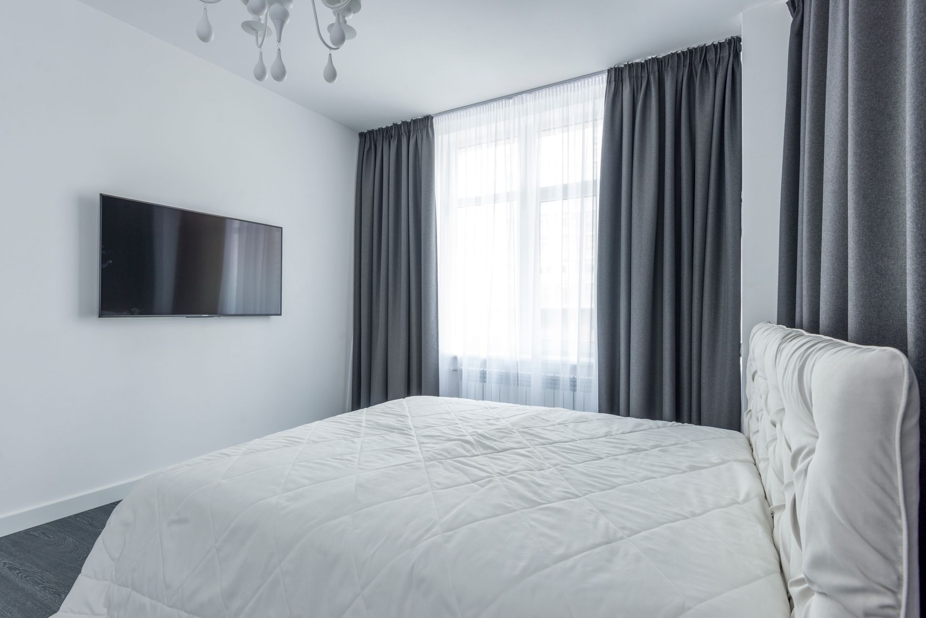 A modern bedroom featuring minimalist decor with elegant window curtains.