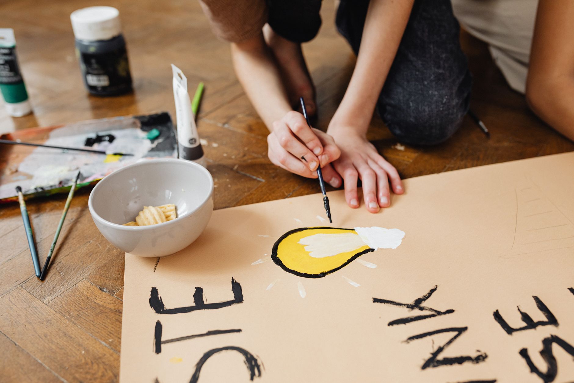 A student is painting a lightbulb for a school art project, focusing on creativity and expression.