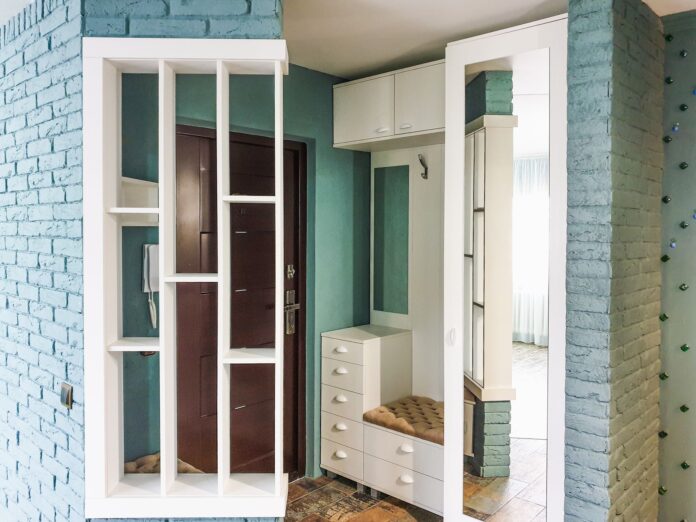 pexels-9551370 Stylish modern entryway with white shelving and brick walls in a home interior.
