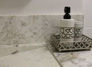 9 Bathroom Countertop Ideas That Blend Style and Durability Stylish bathroom setup featuring a marble countertop and a metallic tray with a geometric design soap dispenser.