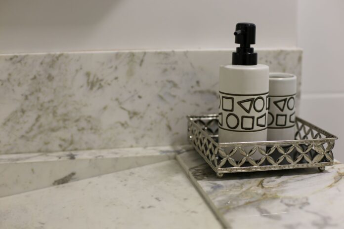 Stylish bathroom setup featuring a marble countertop and a metallic tray with a geometric design soap dispenser.