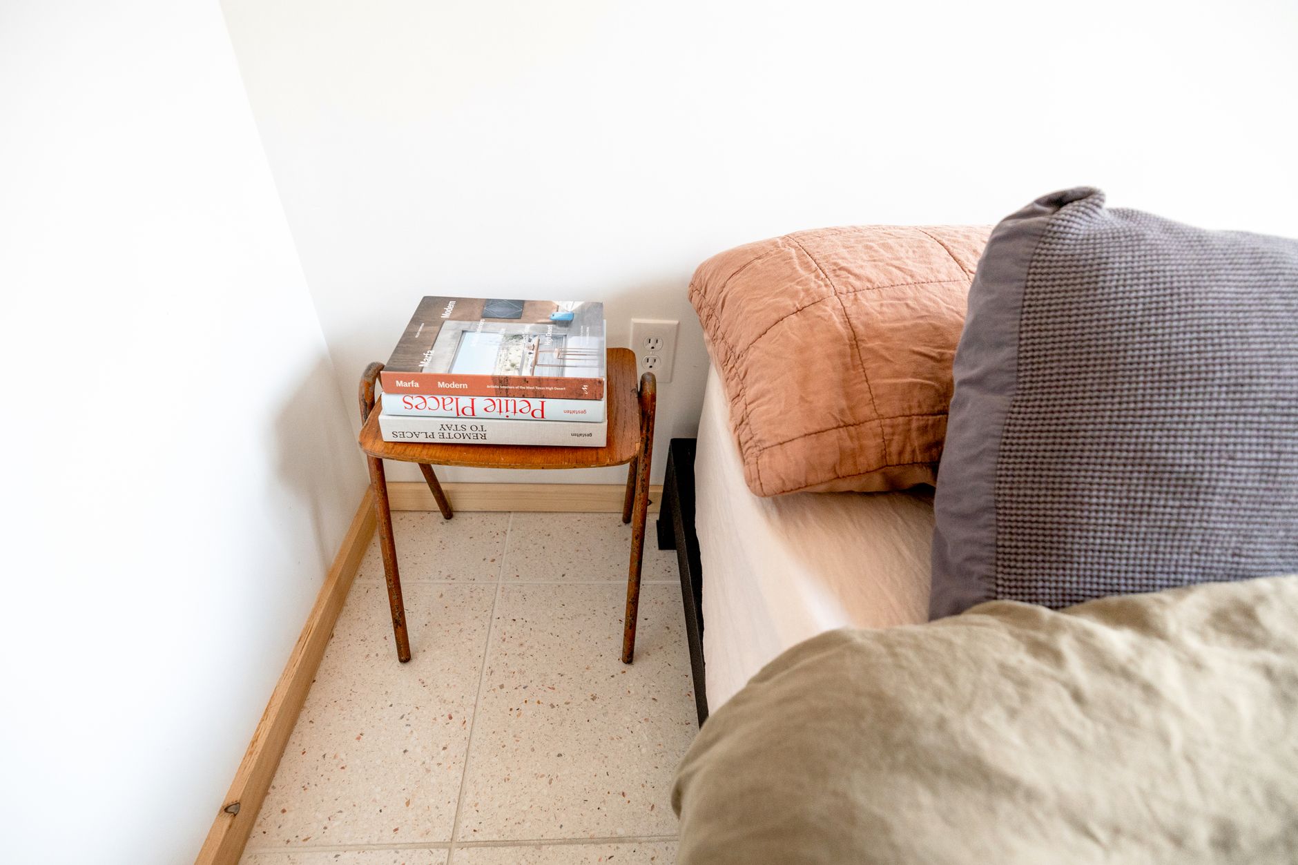 A serene bedroom corner with a wooden bedside table and cozy pillows.
