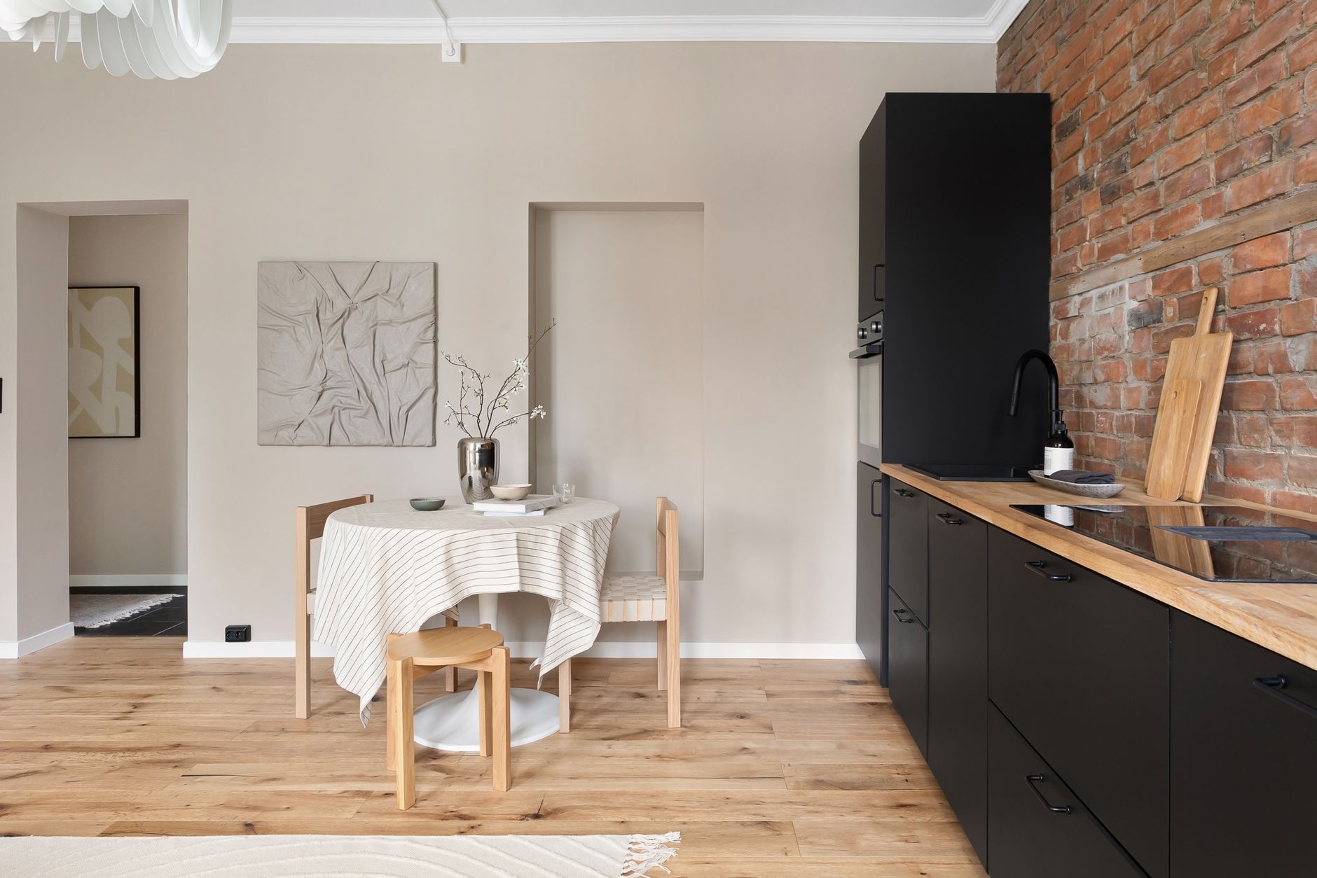 A stylish minimalist kitchen with a table and chairs against a brick wall. Ideal for modern living spaces.