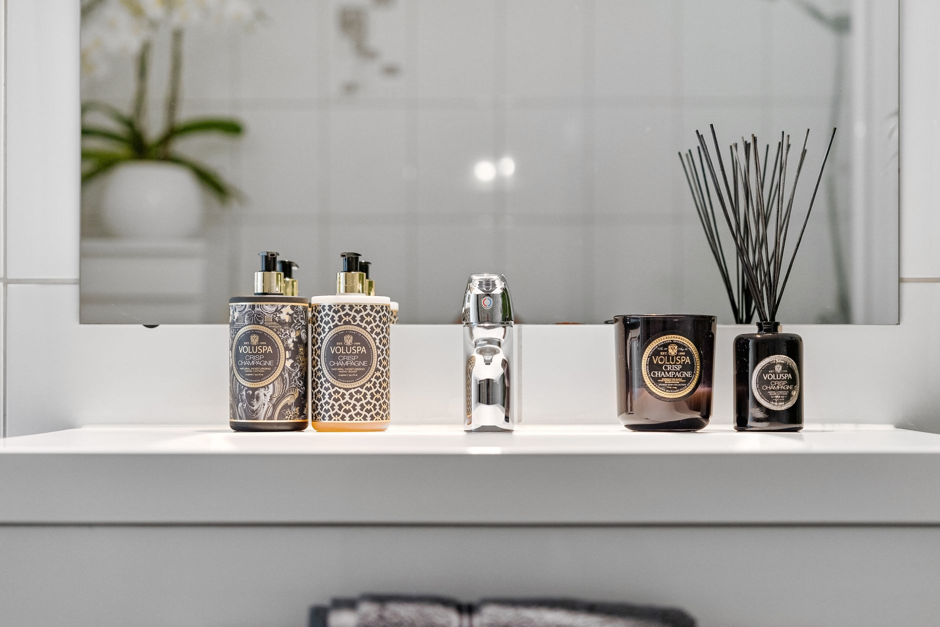 Elegant bathroom display with luxury accessories and sleek reflection.