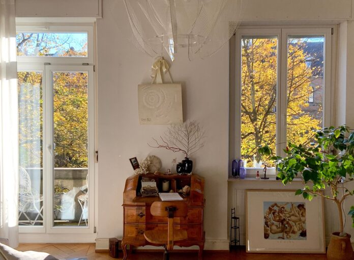 Comfortable home interior with warm sunlight and autumn trees outside the window.