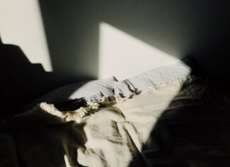 8 Fall Bedding Ideas for a Cozy, Layered Bedroom Retreat A cozy bedroom scene with warm sunlight filtering through, highlighting the soft textures of a bed and blanket.
