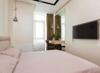 9 Mirror Placement Ideas That Make Small Spaces Feel Twice as Big Comfortable compact bedroom with big mirror near small window with curtains and TV placed on white wall against soft bed in modern apartment