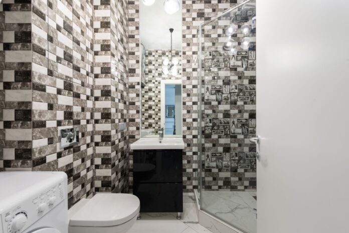 Interior of bright washroom with washing machine near toilet next to shower and sink with tap
