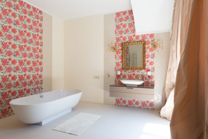 Interior of light spacious luxury bathroom with sink on cabinet under mirror next to soaking bath and carpet
