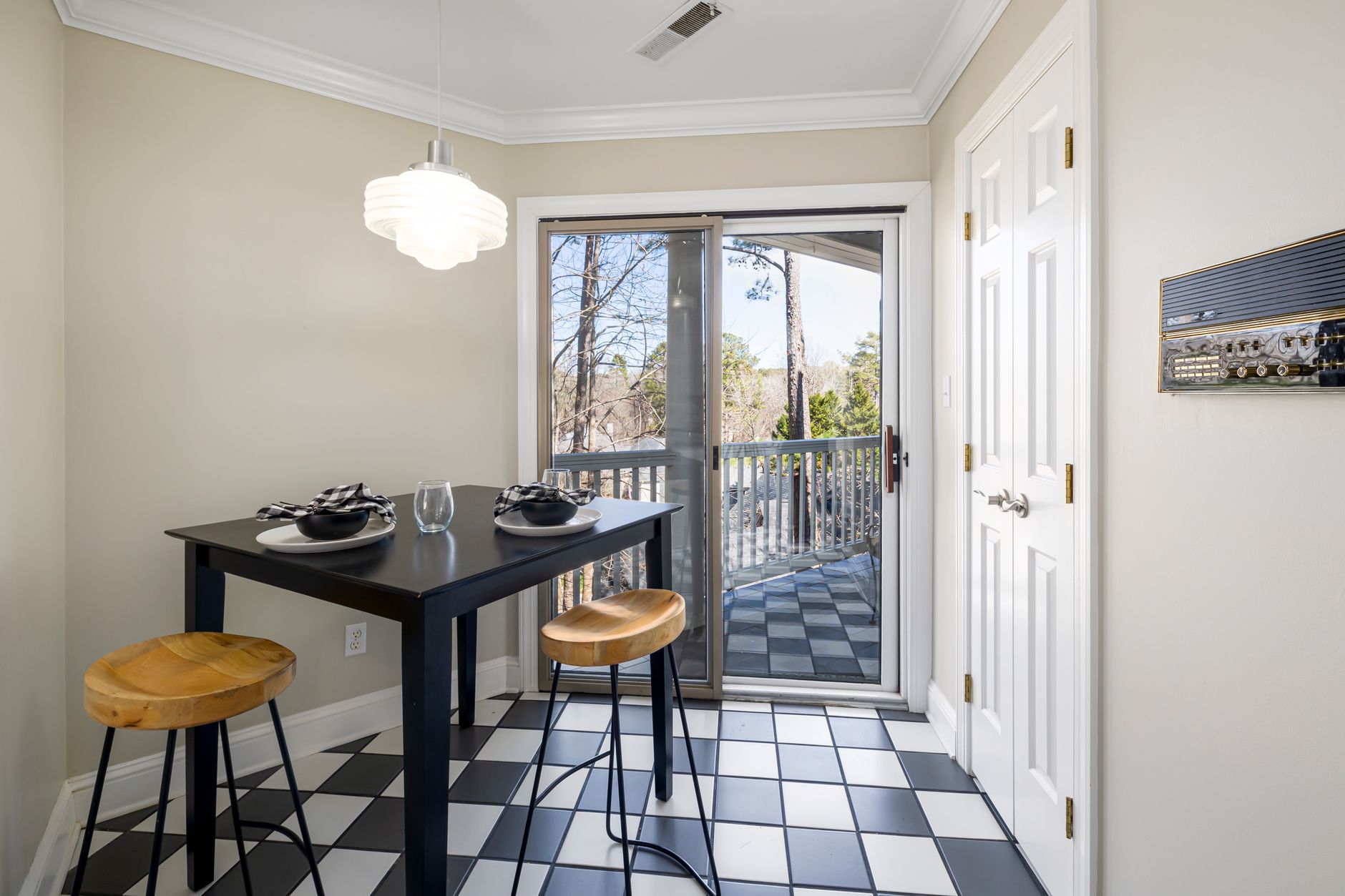 Chic dining nook featuring a black table, wooden stools, and a view to a balcony.