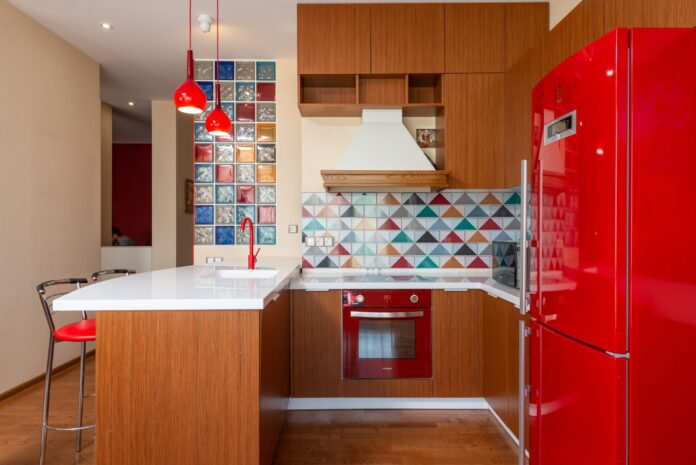 Interior of stylish kitchen with bright furniture and colorful tile in modern apartment in daylight