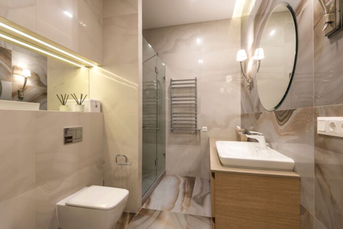 Elegant bathroom with marble tiles, large mirror, and modern fixtures.
