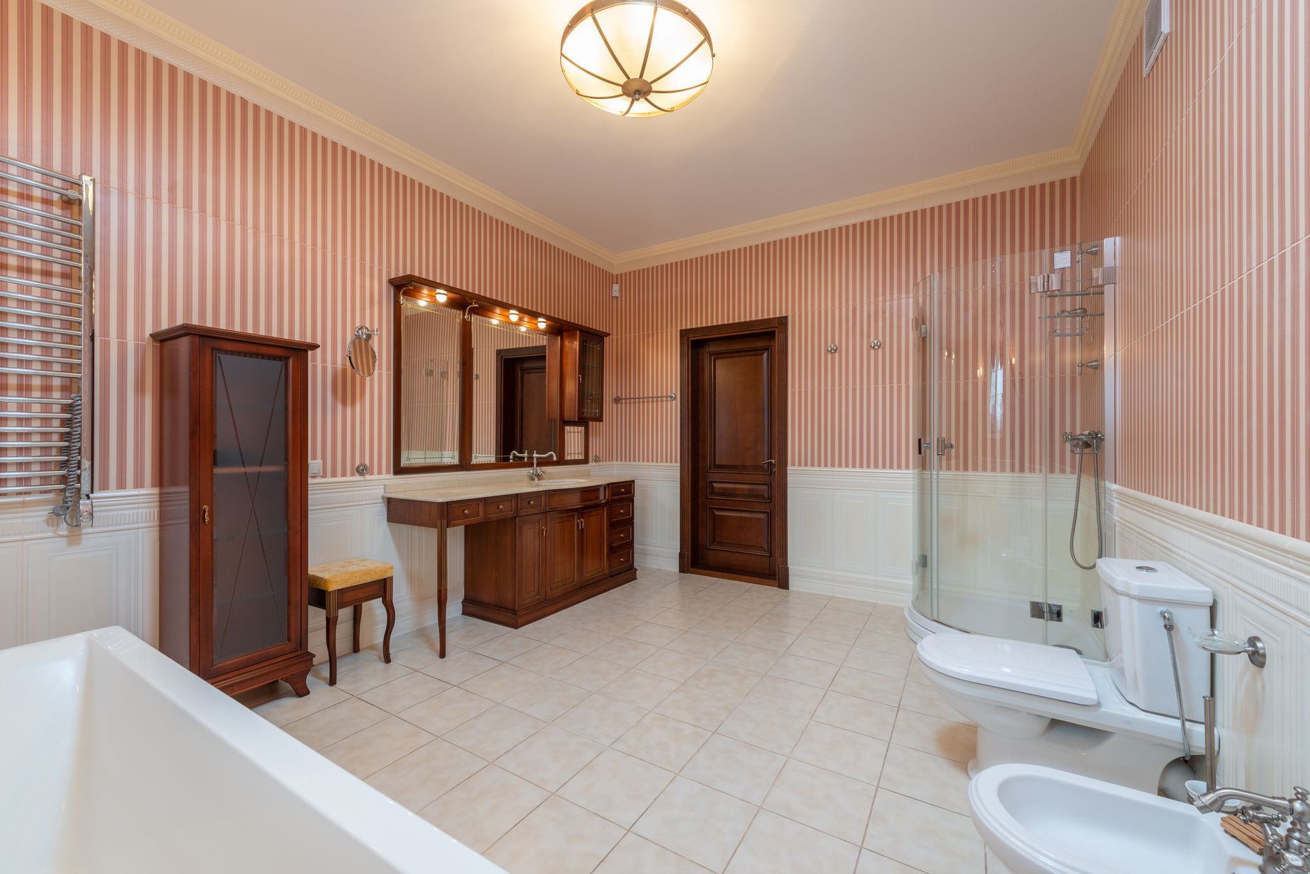 Spacious bathroom with vintage decor, featuring striped wallpaper and wooden furniture