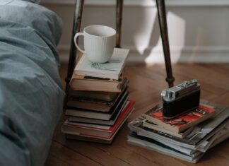 8 Bedroom Reading Nook Ideas for Cozy Autumn Evenings A cozy bedroom corner featuring vintage camera, piles of books, and a white cup, creating an inviting atmosphere.