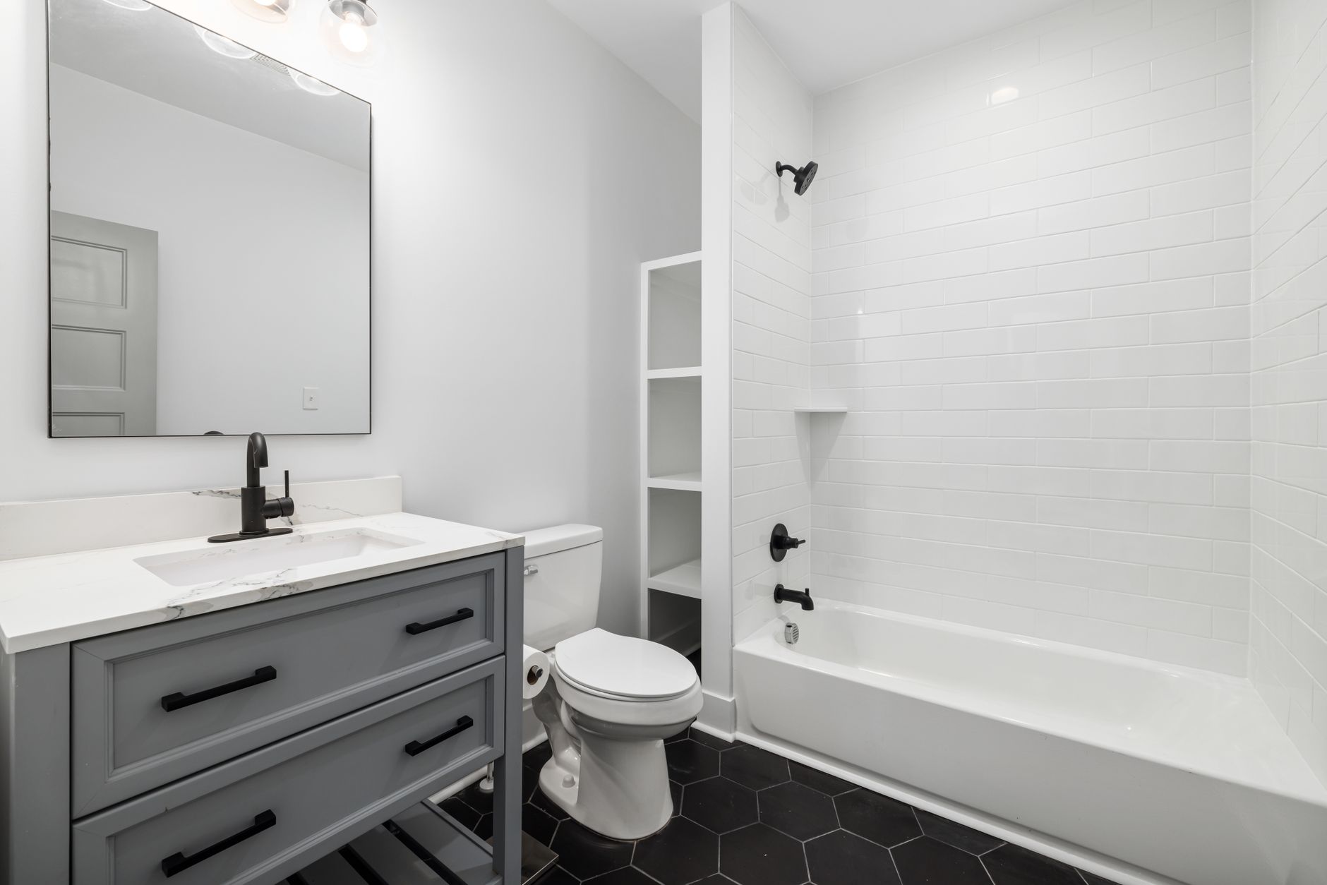 Sleek modern bathroom featuring a white bathtub, sink, toilet, and elegant fixtures.