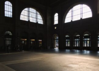 8 Architectural Window Ideas That Flood Your Home With Natural Light Sunlit interior of a spacious building hall with large arched windows casting shadows.