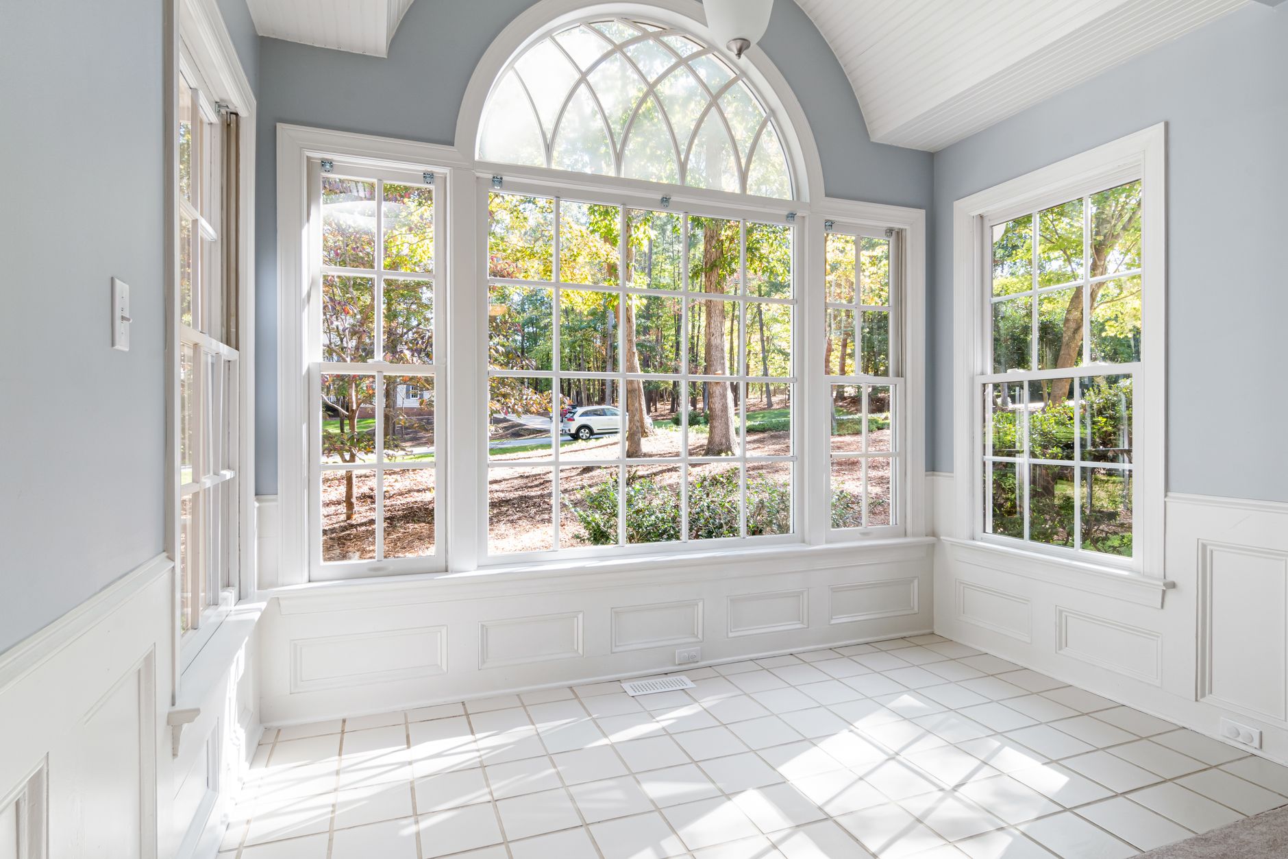 Spacious sunroom with large glass windows offering an outdoor view.